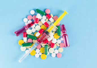 Medicines on a blue background, pills, ampoules, syringe