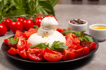 Traditional Italian burrata cheese with salad of delicious cherry tomato, basil leaves and olive oil.