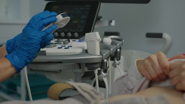 Close-up of an ultrasound sensor in the hand of a female doctor who is conducting a patient examination in the clinic