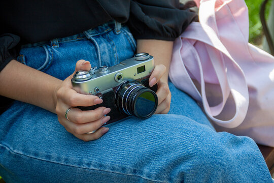 the girl holds a vintage camera in her hands and puts it on her legs