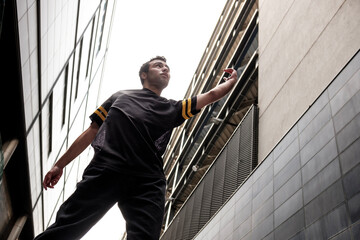 A mixed race young man is dancing between tall building in London.