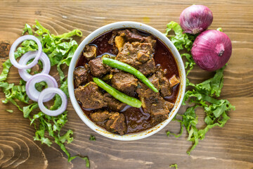 Mezbani Gosht, achar goshat, beef masala karahi, rogan josh with onion, pepper and salad served in a dish isolated on wooden table top view of indian and bangladesh food
