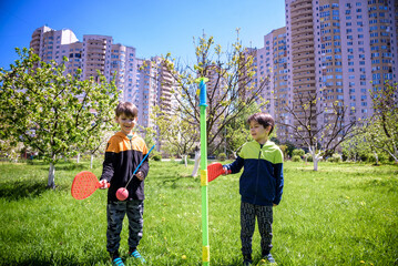 Two friends are playing tetherball swing ball game in summer camping. Two boy brother happy leisure...