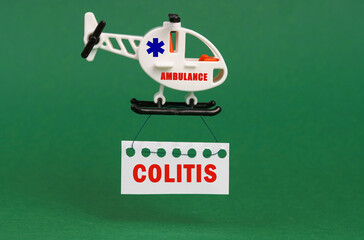 On a green surface, an ambulance helicopter with a sign - COLITIS
