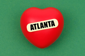 On a green surface lies a red heart with the inscription - Atlanta