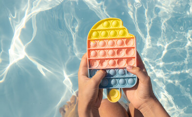 lollipop toy colorful ice cream cone shape against blue clean pool water.little girl teaneeger...