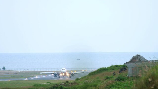 Long shot, passenger plane landing and braking. Runway on the background of the sea