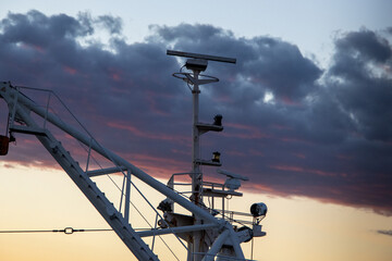 Antenas y radares de barco en el horizonte con las nubes detrás al atardecer en verano