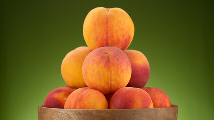 Peaches. Fresh peaches in wooden bowl. Juice peach fruits on green background