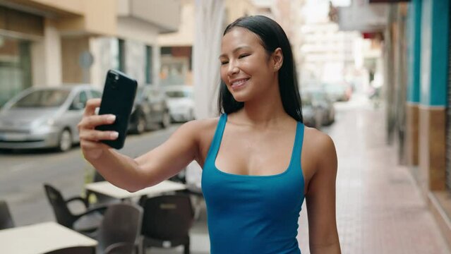 Young beautiful latin woman smiling confident making selfie by the smartphone at street