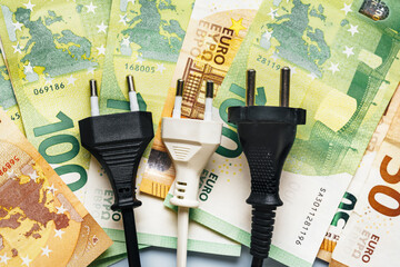 Electrical plug next to euro banknotes showing the drastical increase of costs for electricity. Energy crisis concept in Europe. Top view. CLose up