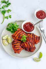 Harissa Grilled Chicken with Condiment Garnished with Cilantro and Lemon Top Down Vertical Photo