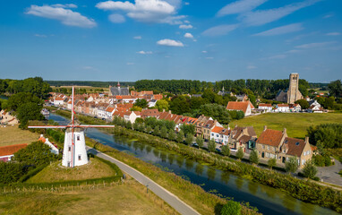 Drone aerial view of the Flemmish city Damme in Belgium, West Flanders Europe with a windmill, canal, church and historic buildings under a blue sky