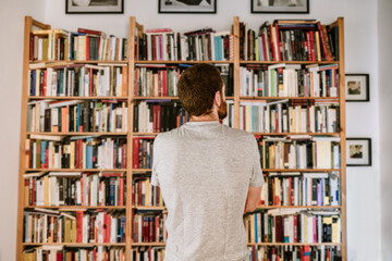 A red head observing his huge book collection at home library