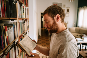 A red head male reading a book at home library