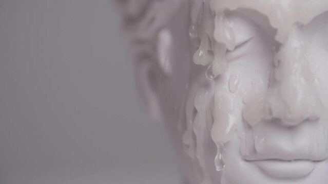 wax pouring over the face of an antique statue in slow motion