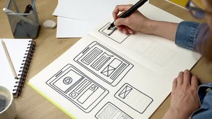 UI designer sketches the user interface of a web application for a mobile phone. A developer creates a prototype for a smartphone.