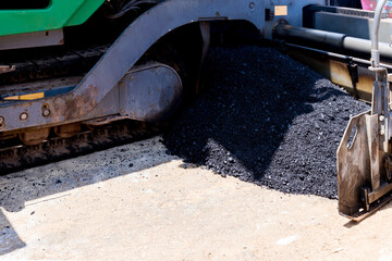 Paver machine on a new asphalt road surface. Laying of a new asphalt pavement on a city street with the use of machinery.