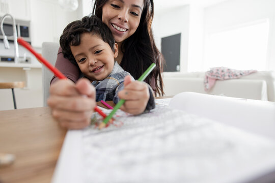 Mother and son coloring together in coloring book at home
