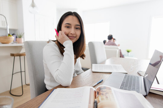 Portrait smiling female college student studying at laptop at home