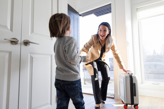 Son running to greet happy mother returning home from business trip