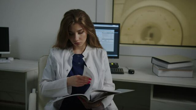 The radiologist sits at the table and studies the patient's case before conducting the examination