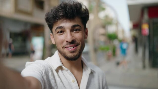 Young arab man smiling confident having video call at street