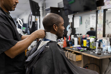 Barber preparing customer for haircut in barber shop