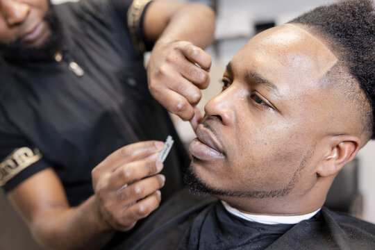 Close Up Barber With Razor Blade Shaving Customer Face In Barber Shop