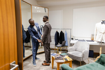 Tailor measuring customer for suit in menswear shop