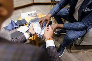 Tailor and customer looking at fabric swatches for custom suit