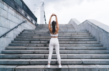 Unrecognizable female athlete warming up on stairway during workout on street - obrazy, fototapety, plakaty