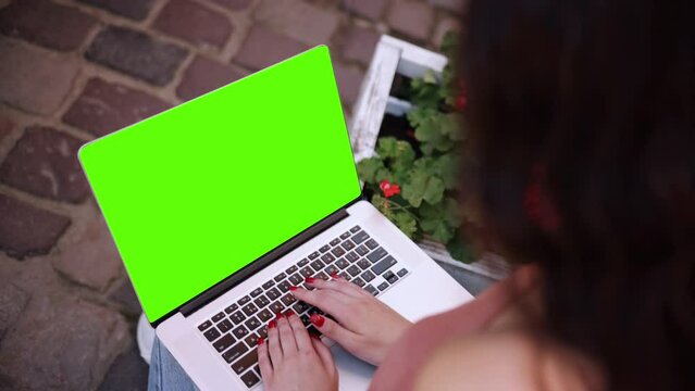 In the background, the woman's hands are working on the green screen computer. Creative people can put whatever they want on computer screens. And the woman's hands are typing on the keyboard outside