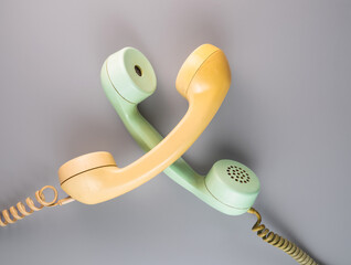 Yellow and green crossed telephone receivers with twisted cords from an old antique rotary phones...