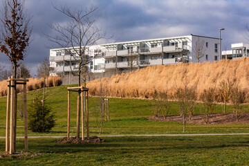 A new building apartment block in front of dark clouds and a green area