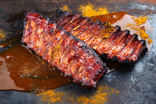 Barbecue pork spare loin ribs St Louis cut with hot honey chili sauce served as close-up on a rustic black board