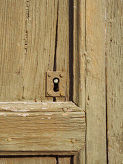 Ancient biege door details with keyhole and peeling paint
