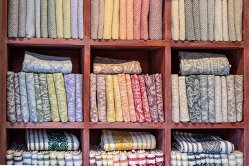 a perfect row of fabrics on wooden shelves. a model of perfectionism, perfect order,