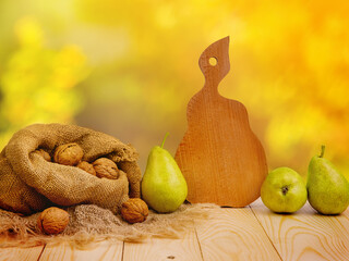 Pear and walnut on the wooden table and pear-shaped cutting board