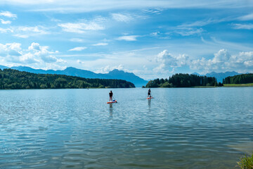 Couple at the Forggensee doing stand up paddling during summer, Bavaria Germany