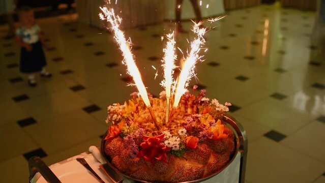 signature dish of restaurant big bread kalach pastries with fried stew on grill burning candles fireworks. presentation of interesting original large dish for a company in a restaurant at a party