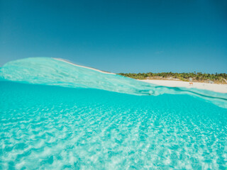 Half underwater shot, clear turquoise water and sunny blue sky. Tropical ocean