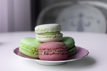 Mix of appetizing macarons on white table decorated with blurred flowers. Dry flowers. Greeting card. Food background. 