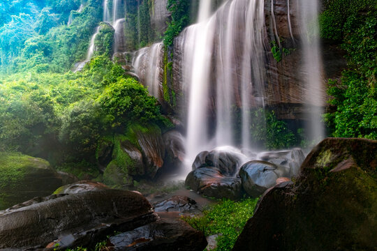 A waterfall flowing through rocks within a lush forest. in Bueng Kan Province, Thailand