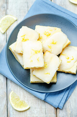 Lemon bars with lemon icing on a wood background
