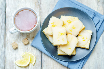 Lemon bars with lemon icing on a wood background