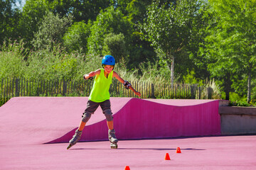 Boy in blue helmet skate fast on rollerblades around cones