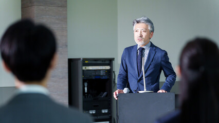 セミナーでプレゼンをするミドルビジネスマン