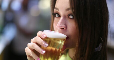 Pretty girl drinking glass of beer. Young woman drinks alcoholic beverage