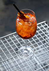Orange Spritz refresher sitting on vintage magazine holder with metal grate. Horizontal shot